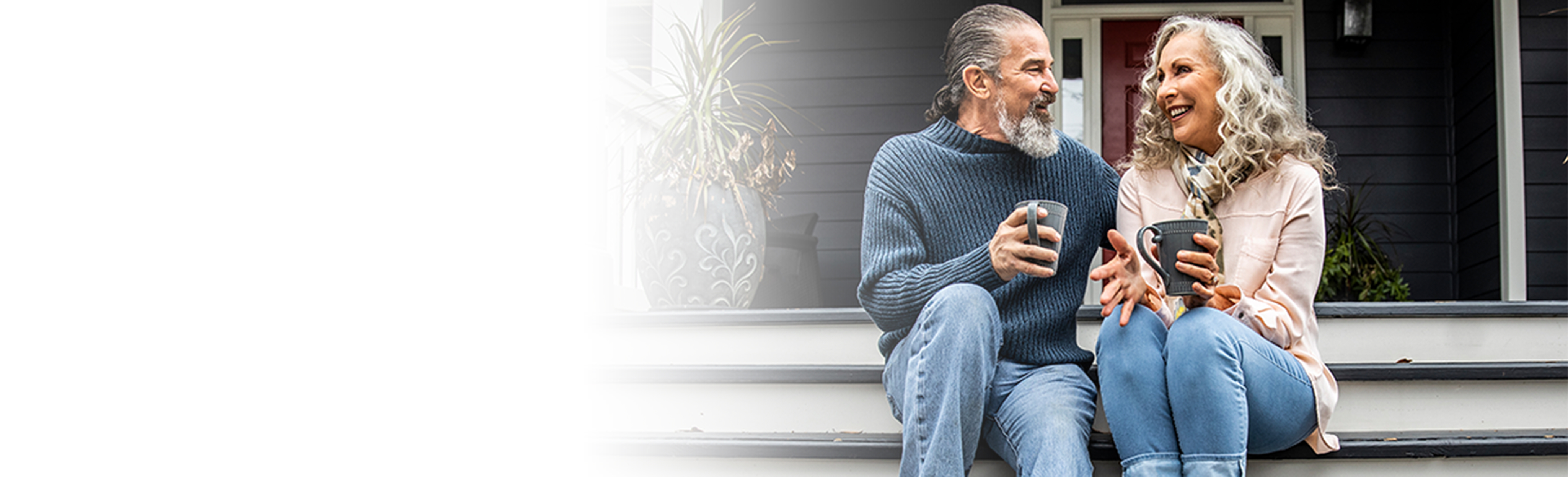 senior couple sitting on their porch enjoying a warm drink